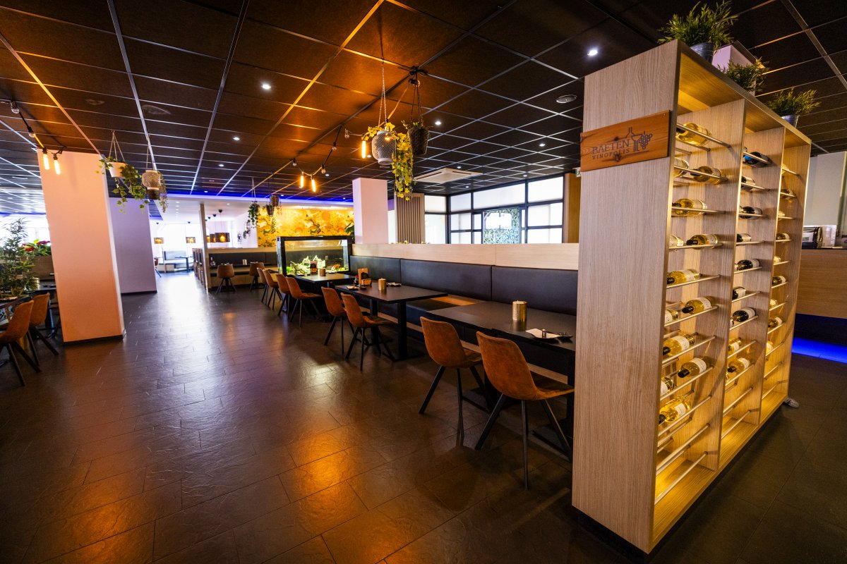 Interieur Interieur van Yumi Sushi & Grill met een moderne en warme uitstraling. Het restaurant beschikt over houten tafels, bruine leren stoelen en sfeervolle verlichting. Opvallende elementen is het wijnrek en het aquarium. Hangende planten zorgen voor een stijlvolle en ontspannen ambiance.