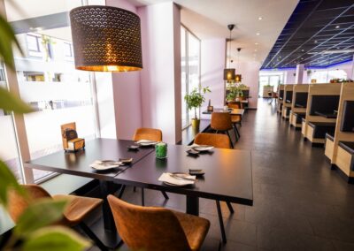 Het interieur van Yumi Sushi & Grill straalt een eigentijdse en warme sfeer uit. De ruimte biedt zowel comfortabele booth-zitplaatsen met houten panelen en zwarte kussens als losse tafels aan het raam met uitzicht op de omgeving.